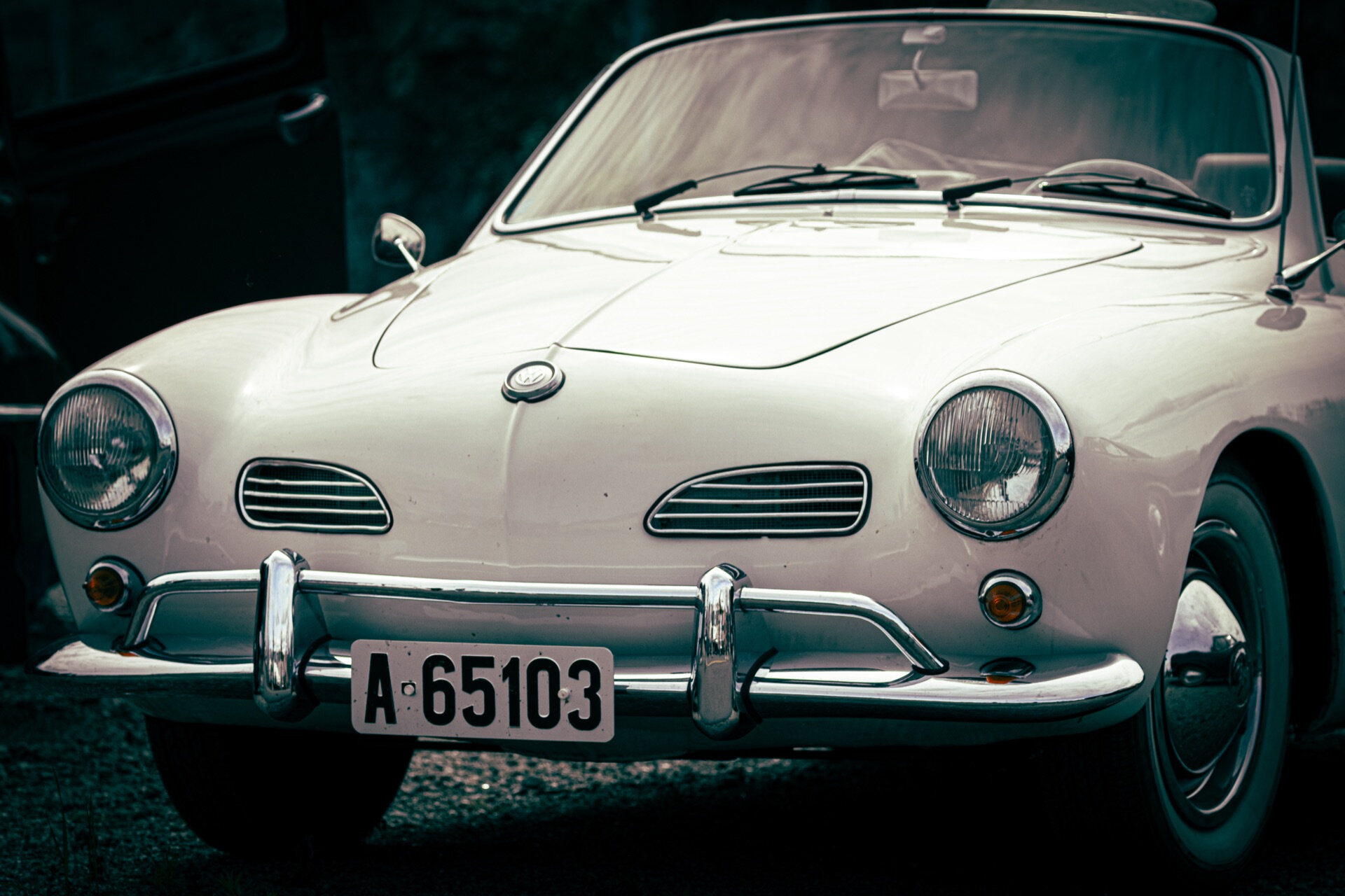 Hvit Volkswagen Karmann Ghia cabriolet fotografert forfra i mørk bakgrunn