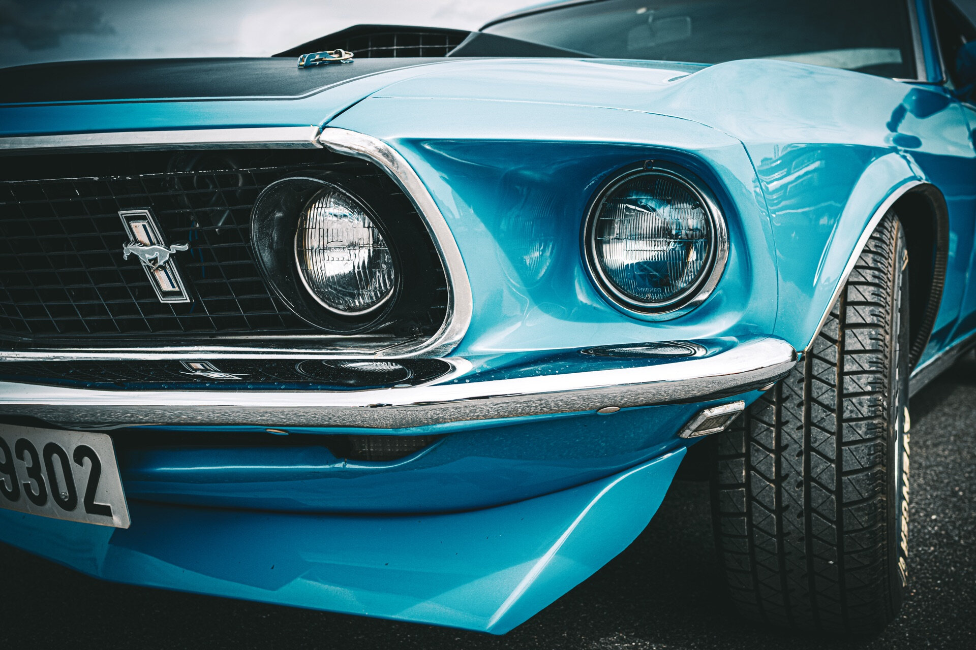 Turkis Ford Mustang med doble frontlys og hestesymbol i nærbilde