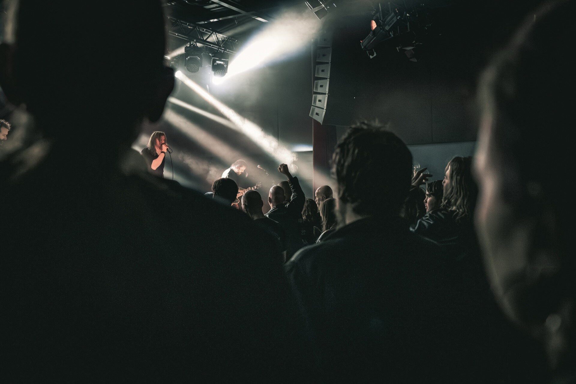 Publikum med knyttede never løftet i varmt motlys på konsert