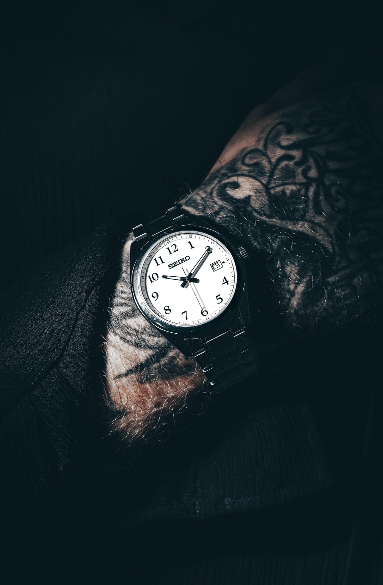 Seiko armbåndsur på tatovert håndledd i mørk stemningsfull belysning